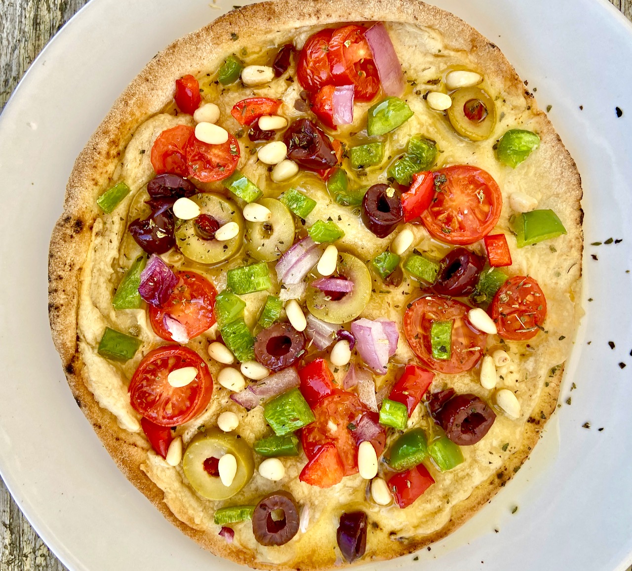 Savory pita spread with a tahini-lemon spread , topped with olives, tomatoes, green pepper and onion